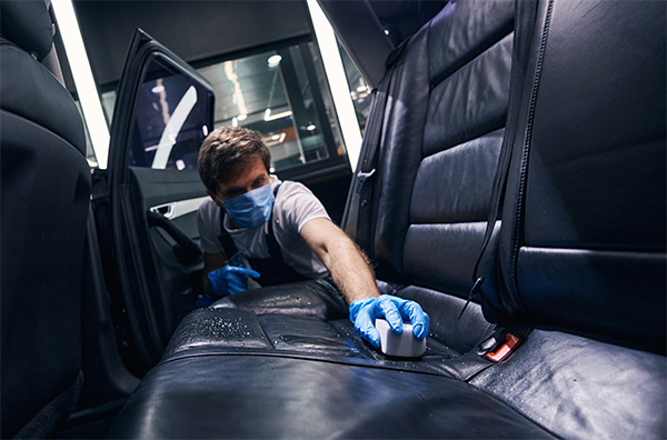 Man applying leather treatment to car seat